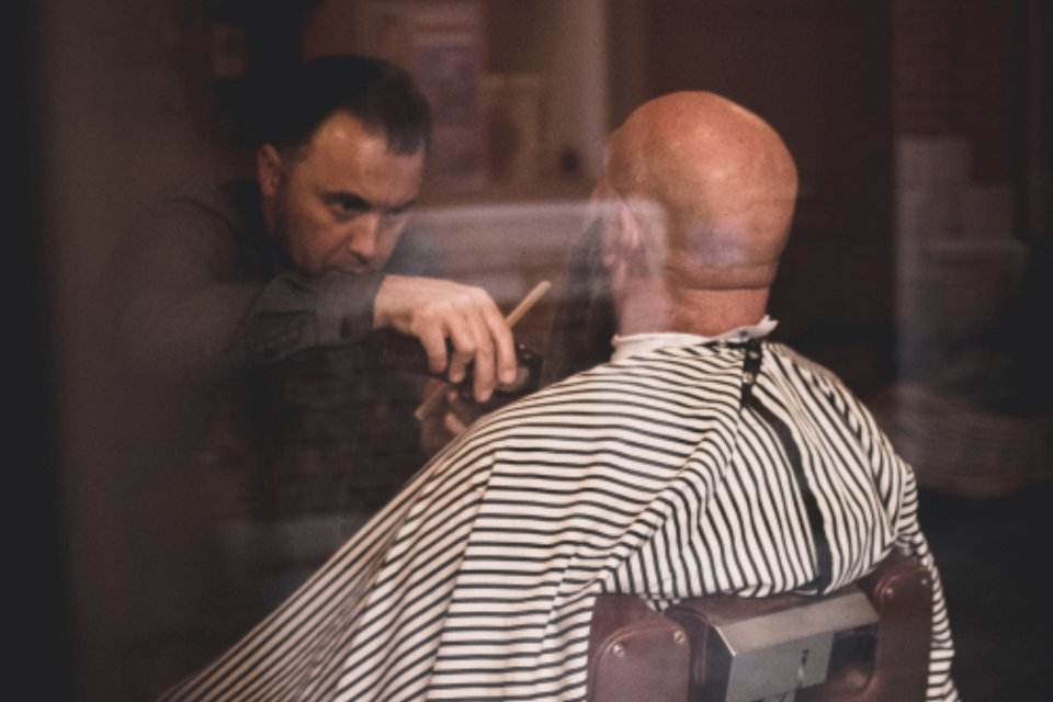 A barber at work on a client in his shop